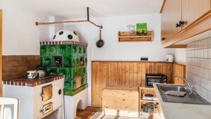 A compact kitchen with a vintage stove, wooden cabinets, a wooden bench, and a small sink.