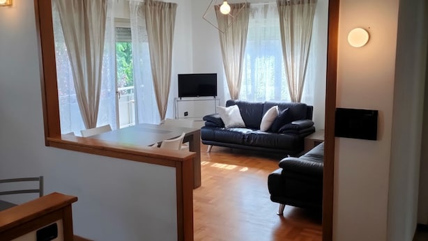 Una sala de estar moderna con un sofá, televisor y un comedor con mesa y sillas.