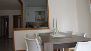 Un comedor con un espejo grande, una mesa con sillas blancas y un centro de mesa con flores.
