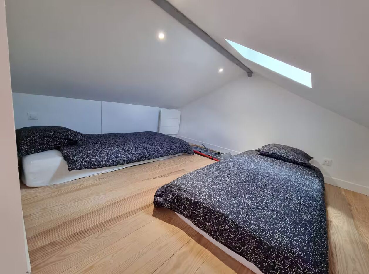 Ein kleines, modernes Schlafzimmer mit zwei Betten, einem Oberlicht und Holzboden.