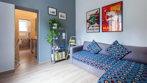 En moderne stue med en grå sofa, mønstrede puder, en bogreol og to billeder i rammer på væggen.