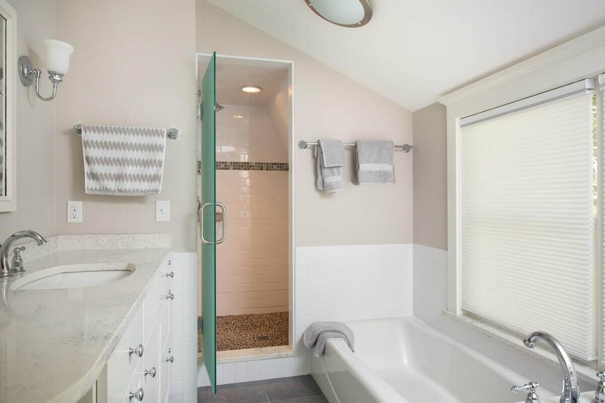 A bathroom with a bathtub, a shower, a sink, and a towel rack.