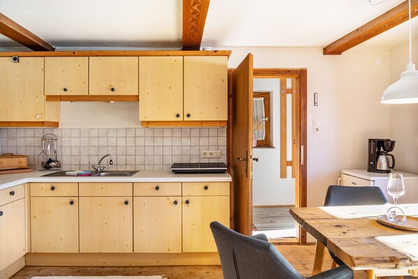 Una cocina con armarios de madera, un lavamanos y un comedor con una mesa y sillas.