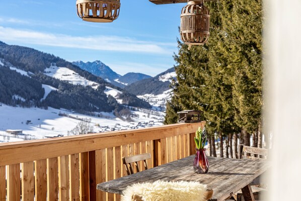 A wooden deck with a table, chairs, and a vase with flowers.
