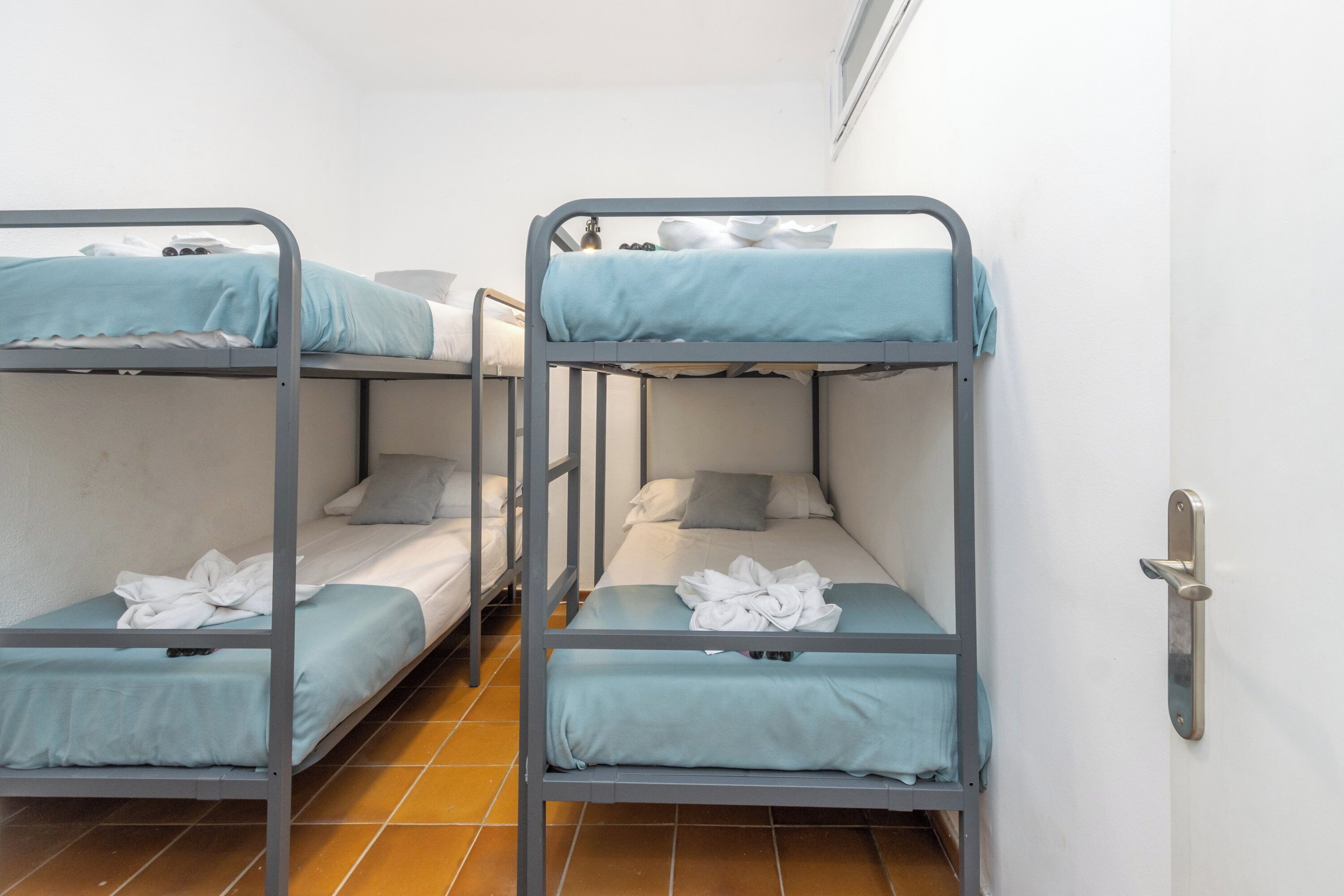 A room with three bunk beds, each with a blue mattress and white bedding.