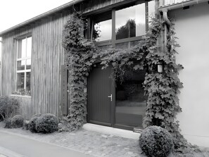 Un edificio con fachada de madera, una puerta oscura y una ventana con un letrero que dice 'CHAMBRES D'HOTES'.