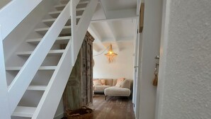 A staircase with white railings leading to a living room with a sofa and a hanging light fixture. - Casa Nieuwendamme, dogs allowed and a few steps from Nieuwpoort (Nieuwpoort)