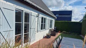 A light blue house with white shutters, a paved patio, and a garden with potted plants. - Casa Nieuwendamme, dogs allowed and a few steps from Nieuwpoort (Nieuwpoort)