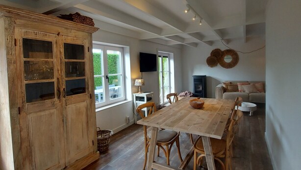 A spacious dining area with a wooden table and chairs, a large wooden cabinet, and a television mounted on the wall. - Casa Nieuwendamme, dogs allowed and a few steps from Nieuwpoort (Nieuwpoort)