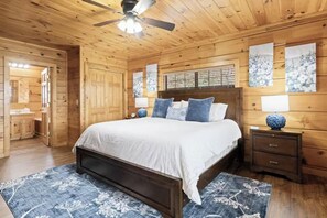 Un dormitorio con paneles de madera, una cama, mesitas de noche y obras de arte en las paredes.