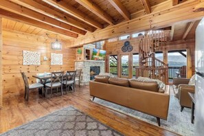 Un interior de madera con chimenea, un sofá y una zona de comedor.