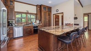 Una cocina con armarios de madera, una isla grande con taburetes de bar y un reloj en la pared.
