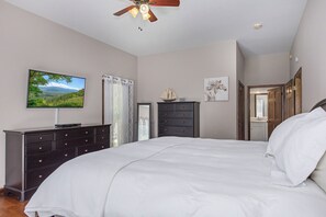 A bedroom with a bed, a dresser, a television, and a ceiling fan. - Experience the Ultimate Luxury Retreat on the Little Pigeon River (Sevierville)