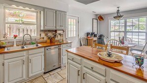 Una cucina con mobili bianchi, un piano di lavoro in legno e un'area pranzo con tavolo e sedie.