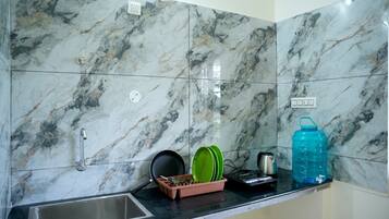 A kitchen with marble backsplash, a sink, and various kitchen items on the counter.