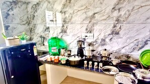 A kitchen with marble tiles, a refrigerator, and various kitchen utensils and appliances. - Kumbha Nivas (Kumbakonam)