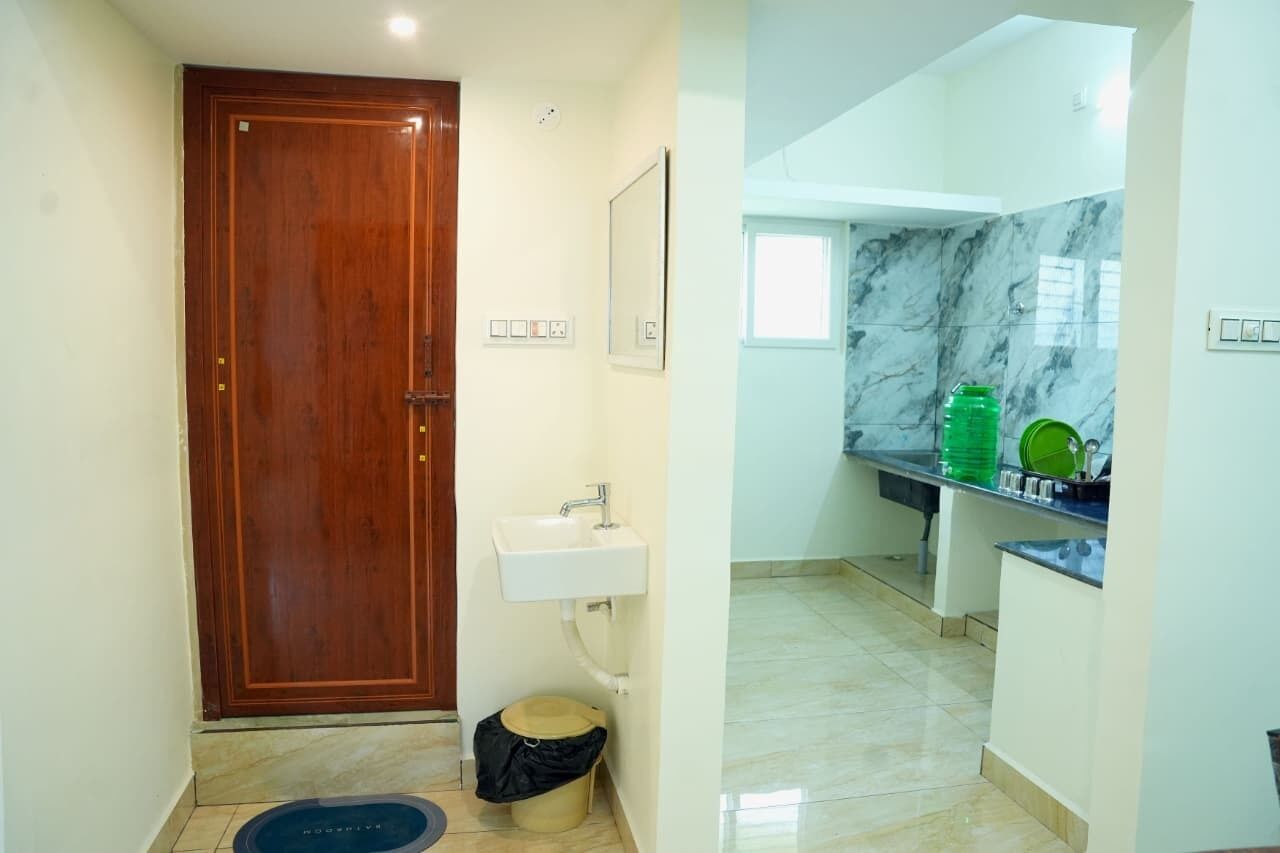 Une salle de bain avec une porte en bois, un lavabo, un miroir et un sol carrelé.