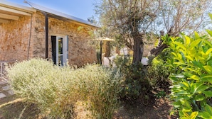 A stone building with a door, surrounded by greenery and a tree. - Core Resort - 3 Apartment with Shared Pool, Wi-Fi, and Air Conditioning (Tuglie)