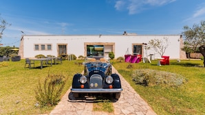 A vintage car parked in front of a modern house with a paved driveway. - Core Resort - 3 Apartment with Shared Pool, Wi-Fi, and Air Conditioning (Tuglie)