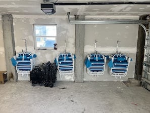 A garage with four blue and white baby strollers hanging on the wall, a window, and a concrete floor. - The Finn at Coconut Cove (Fort Myers Beach)
