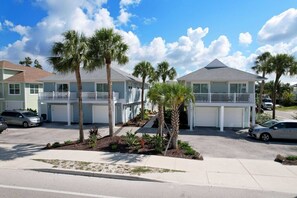 A two-story motel with a central driveway, palm trees, and a clear sky. - The Finn at Coconut Cove (Fort Myers Beach)