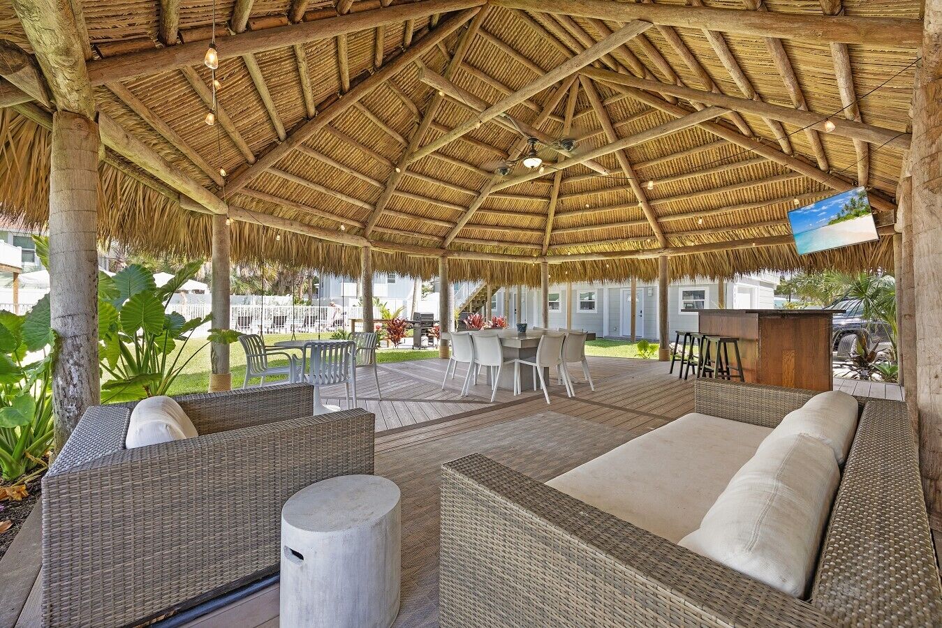 Un espacio de estar techado al aire libre con muebles de mimbre y techo de paja.