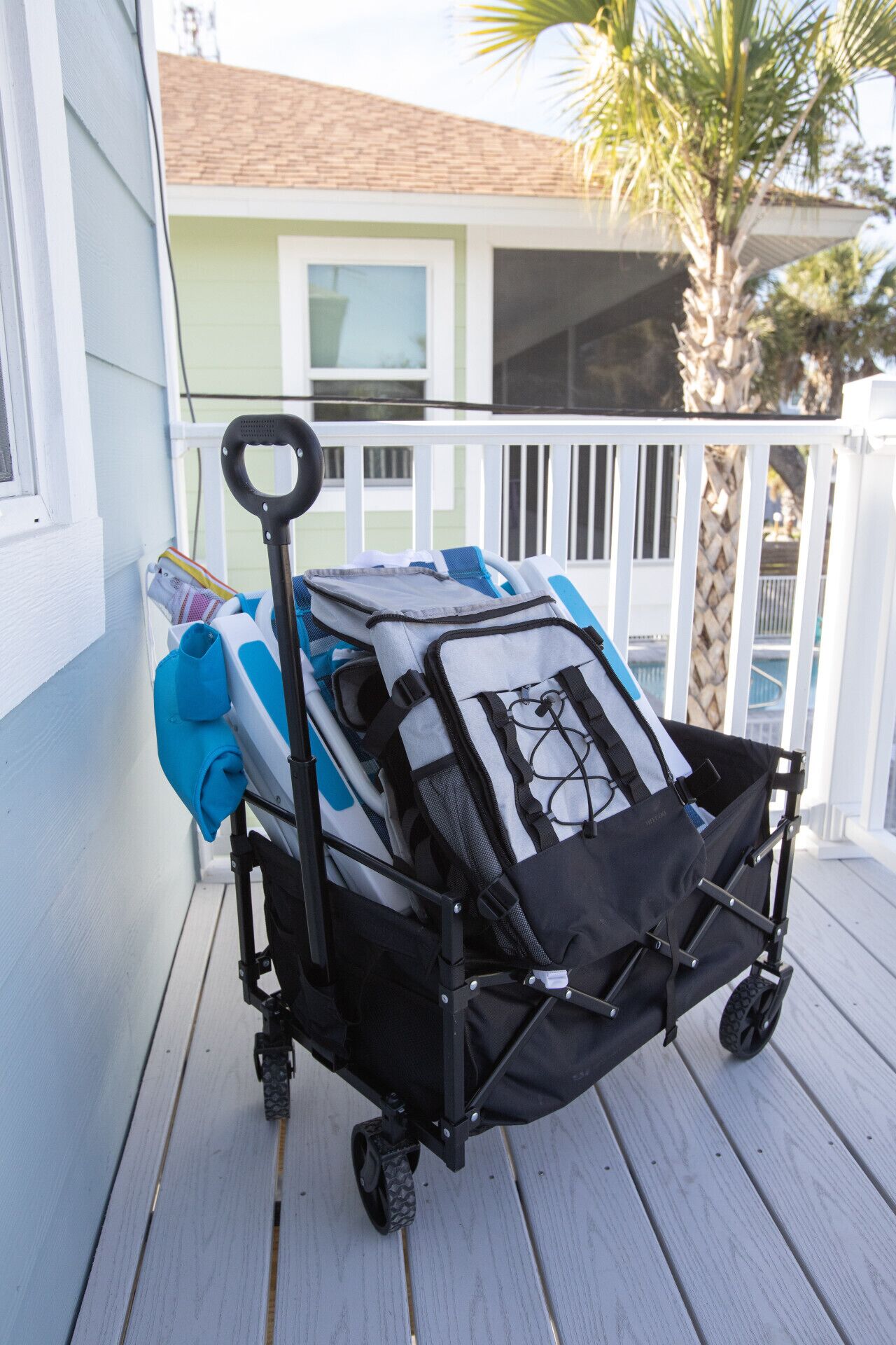 A baby stroller with a black frame and a mesh basket, parked on a wooden deck.