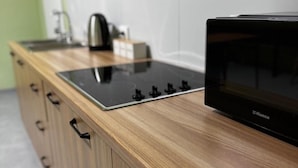 Une cuisine avec un micro-ondes noir, une cuisinière et des armoires en bois.