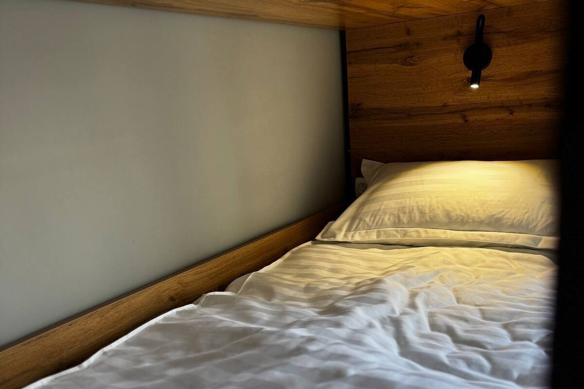 Una cama individual con cabecera de madera en una habitación con techo inclinado.