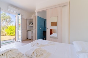 A hotel room with a bed, a bathroom with blue tiles, a small kitchenette, and a sliding glass door to the outside. - Apartment 'Core Resort - 5' with Shared Pool, Wi-Fi and Air Conditioning (Tuglie)