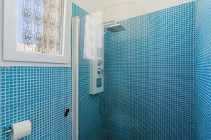 A bathroom with blue tiled walls, a shower, and a window with a curtain. - Apartment 'Core Resort - 5' with Shared Pool, Wi-Fi and Air Conditioning (Tuglie)