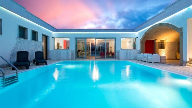 Ein Poolbereich mit freiem Blick auf den Pool, ein überdachter Sitzbereich und ein Gebäudeeingang.