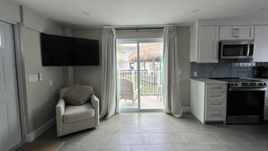 Een moderne keuken met een flatscreen televisie, een eethoek met een stoel en een schuifdeur naar een buitenruimte.