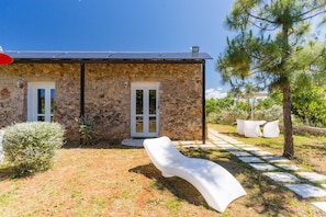 A stone building with a stone facade, a white door, and a paved pathway leading to outdoor seating. - Apartment 'Core Resort - 7' with Shared Pool, Wi-Fi and Air Conditioning (Tuglie)