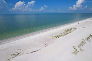 A beach with clear turquoise water and white sand. - The Dex at Coconut Cove (Fort Myers Beach)
