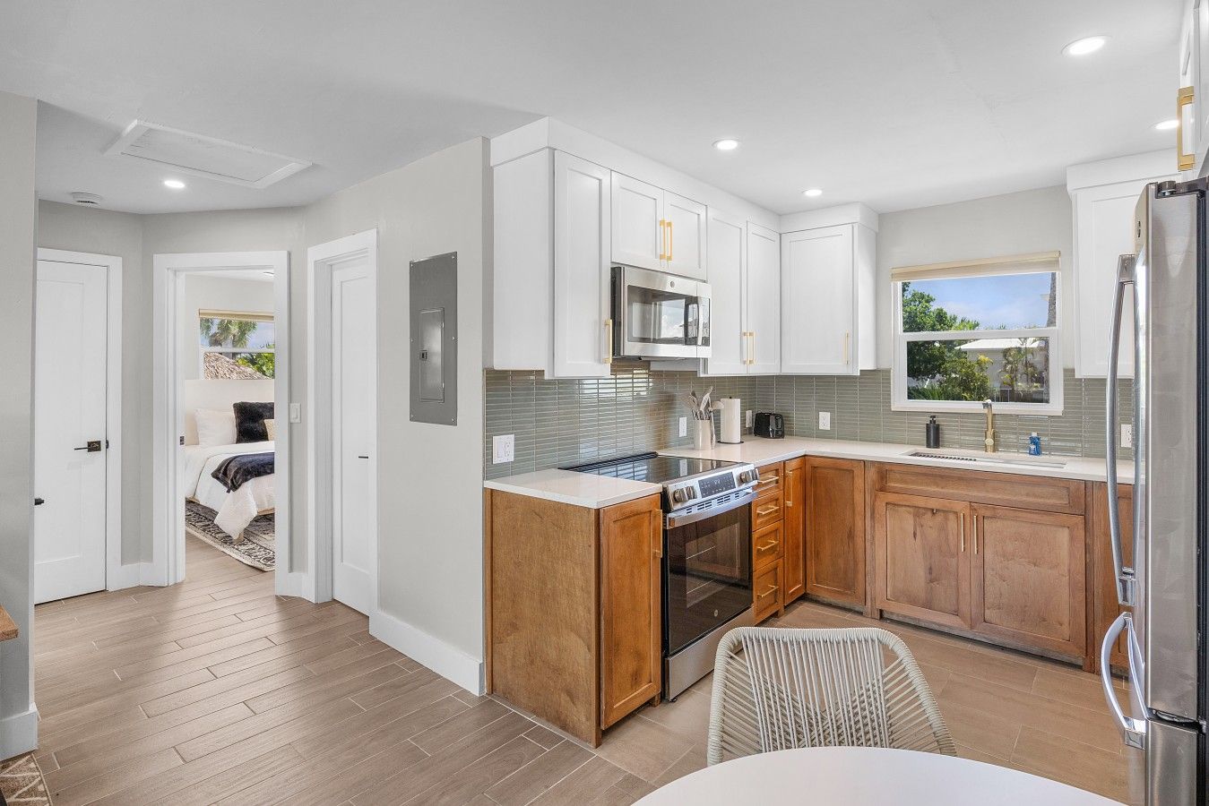 A modern kitchen with white cabinetry, a stainless steel refrigerator, and a built-in oven.