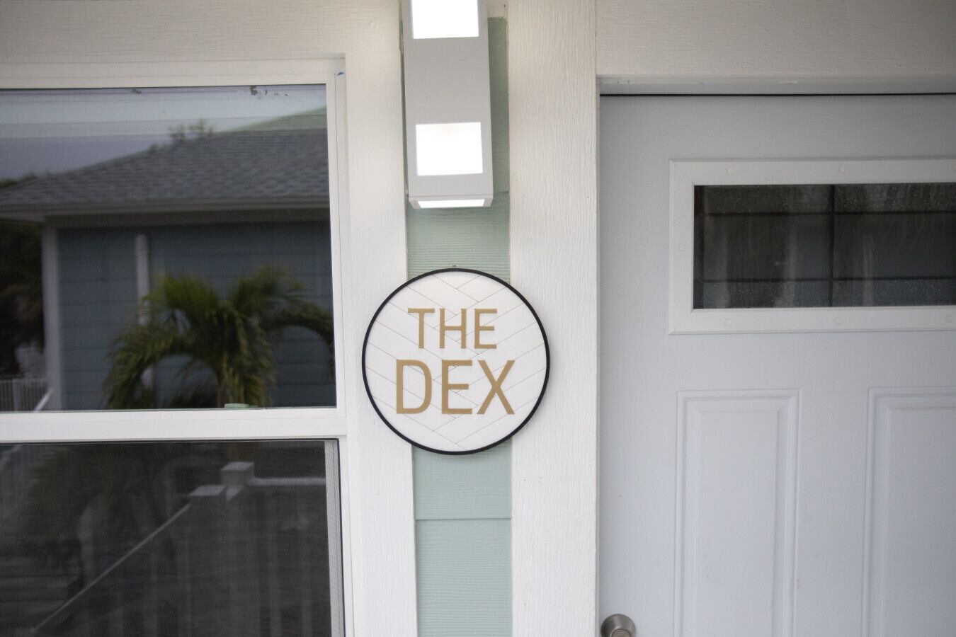 A circular sign with the text "THE DEX" mounted on a white wall.