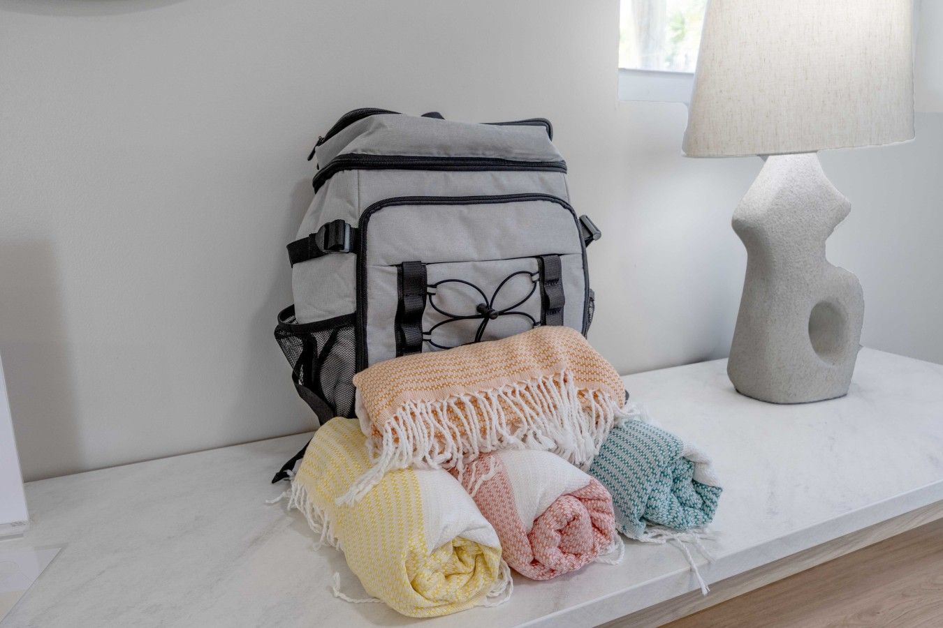 A white bench with a grey backpack and a lamp.