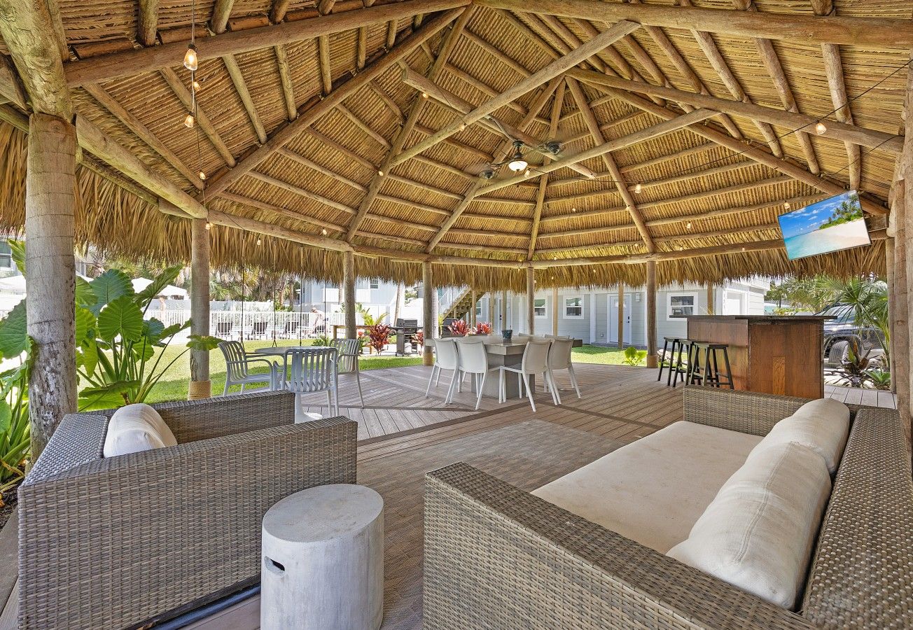 An outdoor seating area with wicker furniture and a thatched roof.
