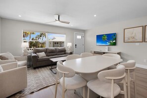 A modern living room with a sofa, chairs, a coffee table, and a TV. - The Wren at Coconut Cove (Fort Myers Beach)