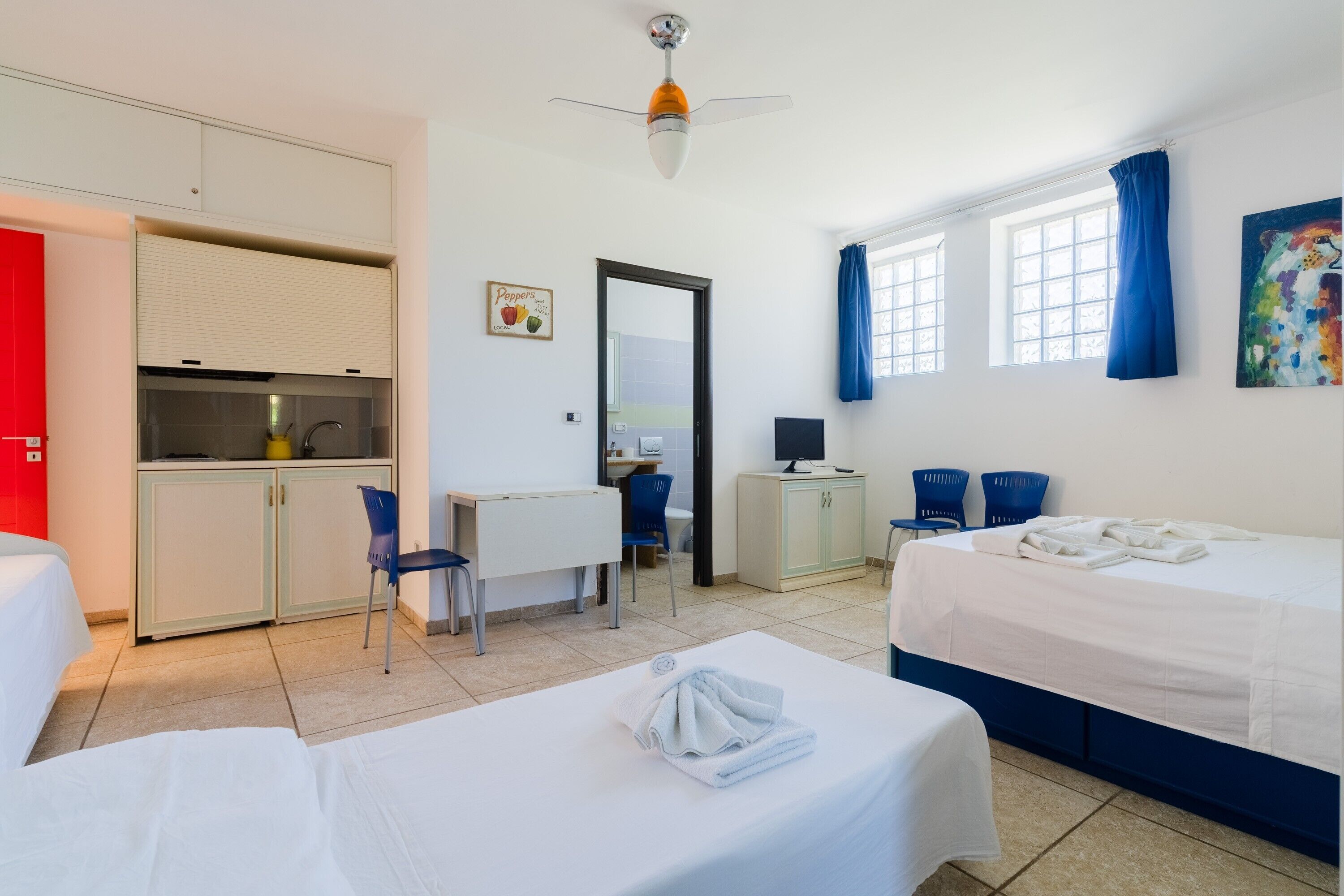 Une chambre d’hôtel avec deux lits, un bureau, une kitchenette et une salle de bain.