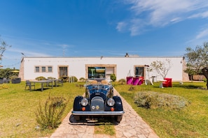 Une voiture ancienne est garée devant une maison moderne, sur une allée dallée.