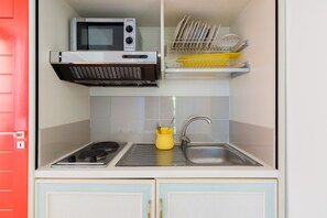 Une cuisine compacte équipée d’un four à micro-ondes, d’une cuisinière, d’un évier et d’un égouttoir à vaisselle.