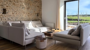 Ein modernes Wohnzimmer mit Steinwand, einem großen Fenster und Blick auf eine grüne Landschaft, im minimalistischen Stil.