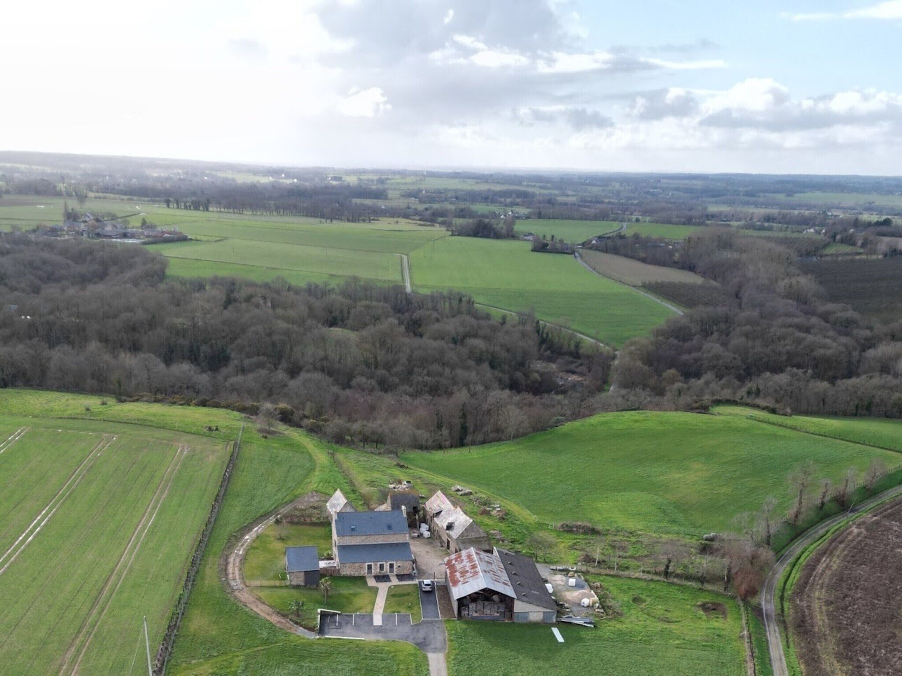 An aerial view of a rural property with a large house surrounded by fields and trees.