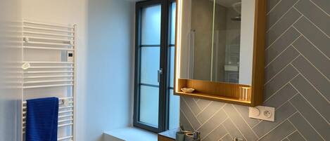 A modern bathroom with a white sink, a mirror, and a window.