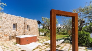 Un edificio de piedra con jacuzzi, banco de madera y estructura de metal.
