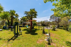 An outdoor gym area with exercise equipment, a slide, and palm trees. - Core Resort - Suite Verde Room with Pool, Shared Terrace, and Wi-Fi (Tuglie)