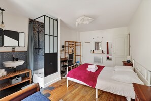 A modern bedroom with a wooden floor, a bed with white and red bedding, a built-in desk, a shower, and a white sink. - Premium 1BR flat with direct access to the RER B (Gentilly)