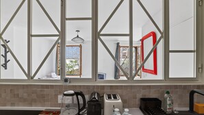 Una cocina con cafetera, tostadora y botellas de agua sobre la encimera.
